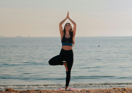 Frau, die am Strand eine aufrechte Yogaposition einnimmt