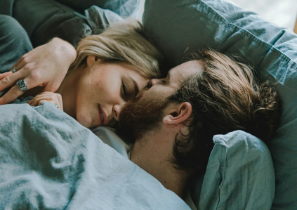 Mann und Frau liegen nebeneinander im Bett und umarmen sich