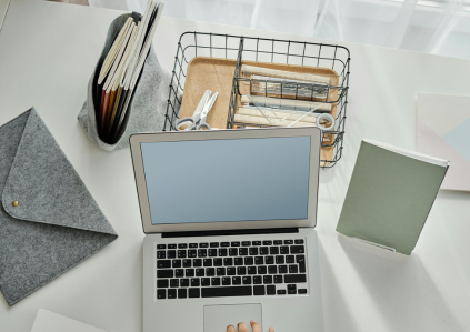 Laptop und Schreibmaterialen auf einem weißen Schreibtisch