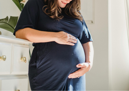 Frau, die ihren schwangeren Bauch hält und ihren Blick auf den Bauch richtet