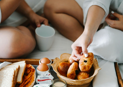 Frühstücktablett mit Eiern und brötchen im Bett und Hände greifen danach